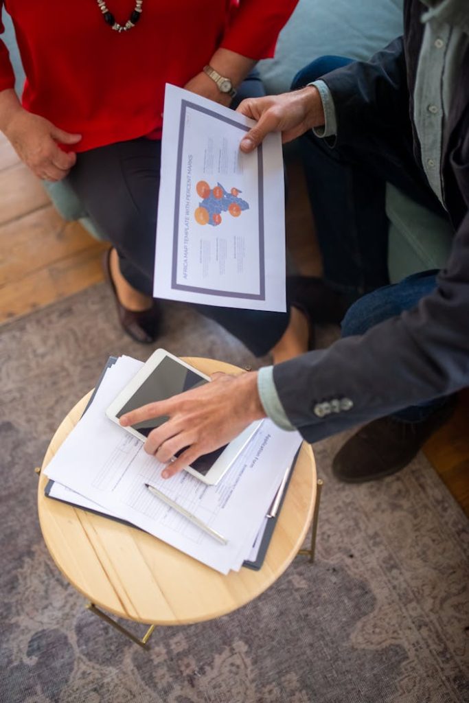 man-holding-a-document-and-a-tablet-on-a-round-table-8439660 Overhead view of a business meeting with documents and a tablet, showcasing collaboration.