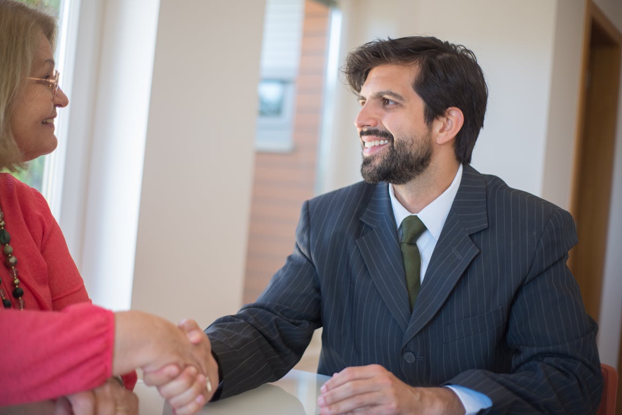The Art of Drawing Readers In: Your attractive post title goes here Professional real estate agent sealing a deal with a senior client indoors through a handshake.