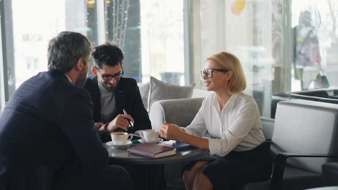 two-men-and-a-woman-sitting-at-a-table-having-a-conversation-yqhnmgl5lag